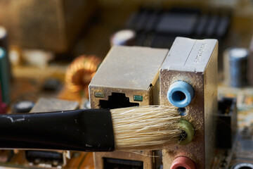 Brush cleaning an old computer board from dust and dirt. Close-up.