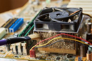 Brush cleaning an old computer board from dust and dirt. Close-up.