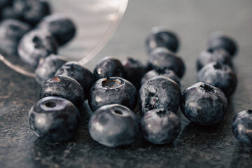 Macro photography, blueberries scattered on a dark surface.