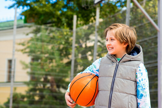 happy schoolboy with basketball ball on the sports ground