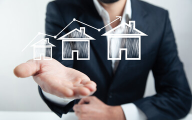 businessman hand protecting increasing size of house models