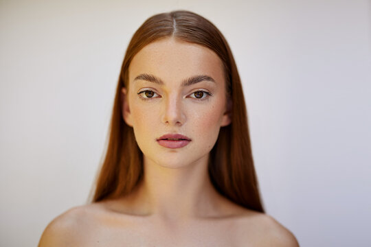 Beauty PhotoshootBeauty photoshoot.  Female model with red hair, brown eyes, freckles, clear skin, against a white backdrop.