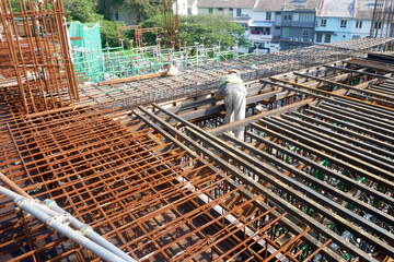 MELAKA, MALAYSIA -JULY 1, 2022: Construction workers are fabricating steel reinforcement bars for floor slabs. Rebar of various sizes is arranged and tied according to the design by the engineer.

