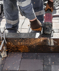 A worker cuts metal at a construction site.