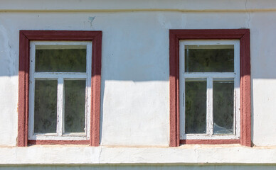 Two windows in the white wall of the house.