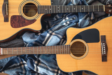 Fototapeta premium Two acoustic guitars on a cozy plaid, top view.