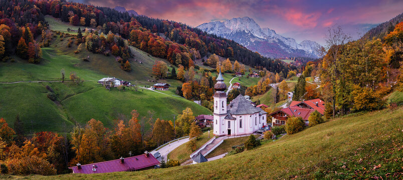 Stunning Autumn landscape during sunset. Scenic panoramic picture-postcard view of famous Maria Gern church in beautiful warm morning light in fall. Vivid atmospheric nature scenery. Nature background