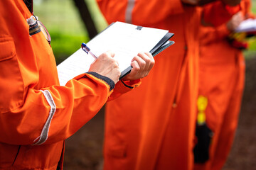 A safety supervisor or manager is writing down on paper for taking note during safety audit at the operation work site. Industrial safety working action scene, close-up and selective focus.