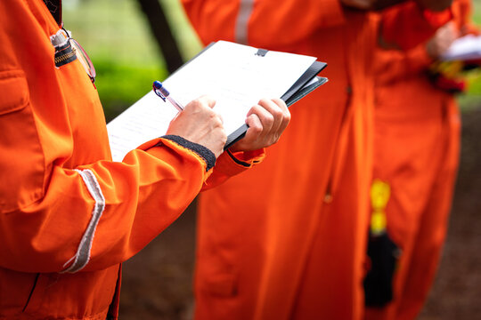 A safety supervisor or manager is writing down on paper for taking note during safety audit at the operation work site. Industrial safety working action scene, close-up and selective focus.