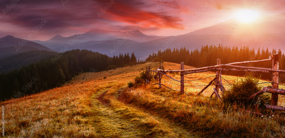 Poster majestic mountains in the distance with lush scenic fields of meadows and a river during sunset. ama
