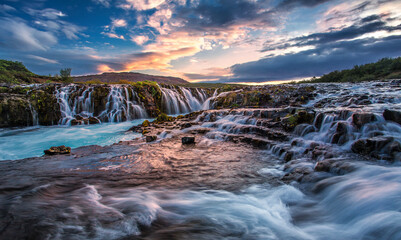 Colorful sunset over the Bruarfoss Waterfall with  picturesque sky during sunset. Amazing nature of Iceland. Iceland is a most popular place of travel.