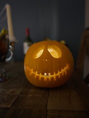 carved pumpkin on table with bottle of wine and candles 