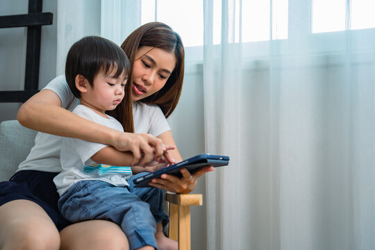 Mother she was opening something on her tablet for her lovely little son to watching in the living room.