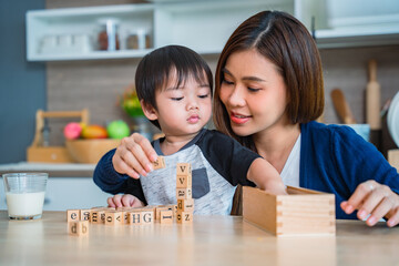 Mother playing dice with her adorable little son in the kitchen.
