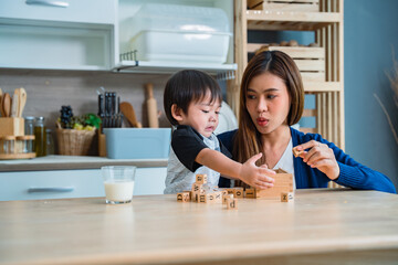 Mother playing dice with her adorable little son in the kitchen.