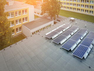 Solar power plant on the school roof. View of the photovoltaic panels against the school buildings,...