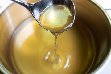 Pouring clear soup bouillon, chicken broth in a pot.