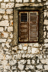 Fototapeta premium Stone wall and window with closed wooden shutters
