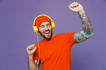 Young happy cool cheerful european man 20s he wearing red hat t-shirt headphones listening music...