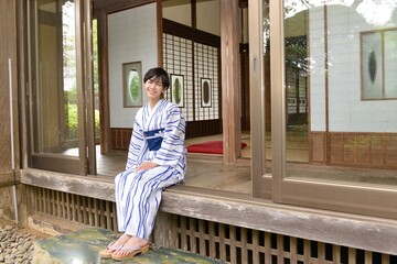 古民家の縁側に座り微笑む浴衣を着た若く綺麗な女性	