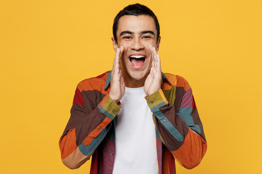 Young promoter middle eastern man 20s he wear casual shirt white t-shirt scream hot news about sales discount with hands near mouth isolated on plain yellow background studio People lifestyle concept.