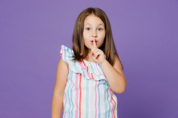 Little secret child kid girl 5-6 year old wears striped dress say hush be quiet finger on lips shhh gesture isolated on plain pastel light purple background Mother's Day love family lifestyle concept