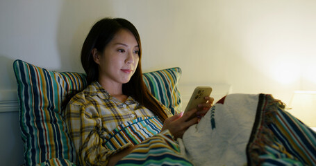 Woman use cellphone on bed at night