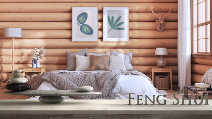 Wooden vintage table shelf with pebble balance and 3d letters making the word feng shui over log cabin wooden bedroom, zen concept interior design