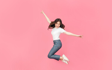 Young Asian woman in a white t-shirt jumping off with her arm raised in air, a cheerful expression...