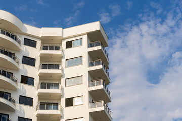 Exterior of a modern apartment building against a blue sky with clouds.