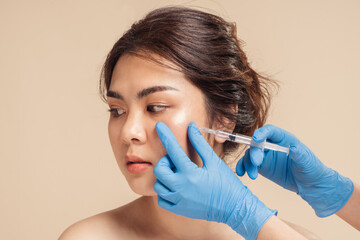 Closeup face young asian woman is getting filler under her eye for anti age wrinkle by a beautician...
