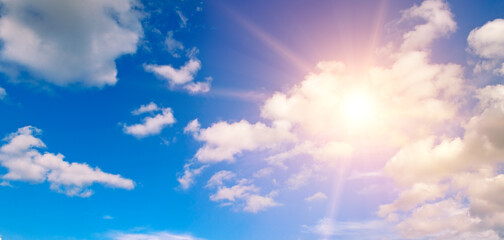 Naklejka na ściany i meble Beautiful, blue sky with fluffy clouds and bright sun as a background