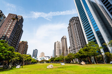 The large park green space in front of the National Taichung Theater in Taiwan and the landscape of modern buildings on both sides.