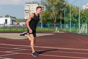 Fototapeta premium Young woman running on the running track at the stadium outdoors
