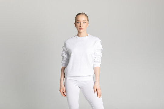 Attractive blonde woman in white sweatshirt and leggings on white background. Mock-up.