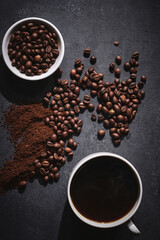 White cup of freshly brewed roasted coffee beans on gray background
