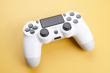 White video game controller, joystick for game console isolated on yellow background. Gamer control device close-up