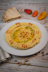 Homemade hummus with tahini plate with olive oil and paprika and pita isolated on brown background. High quality photo