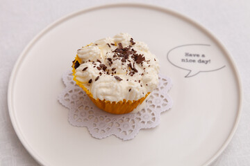 Top view of a cupcake with cream and chocolate chips on a plate with a wish for a good day