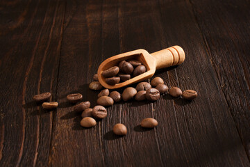 Spoon of coffee beans on wooden background