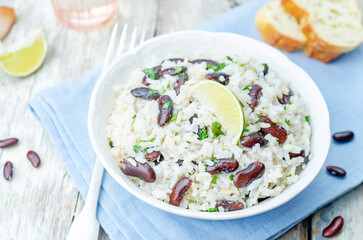 Coconut lime rice with red beans and cilantro in a bowl on a wood background