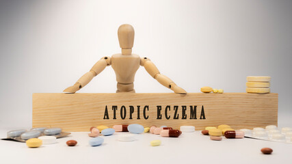 Atopic eczema written on wooden surface. Wooden man and medicine concept. Healthy life and diseases.