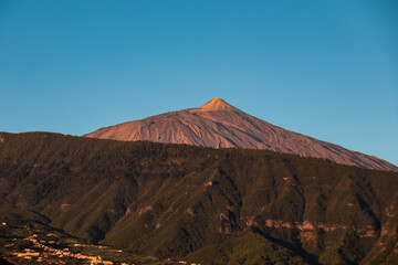 Panoramic view on the peak of volcano Pico del Teide during sunrise seen from the port of Puerto de...