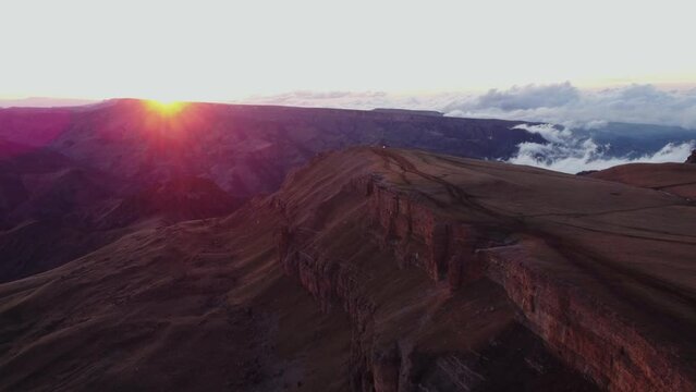 flying above the clouds over the Caucasus mountains at sunset. drone view of the Bermamyt plateau in the evening light in spring.