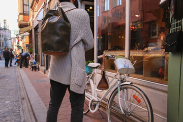 man wearing backpack with back turned and bicycle next to him, custom leather backpack, selective focus