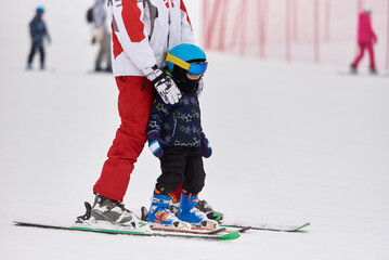 Mom teaches the child to ski on the slope