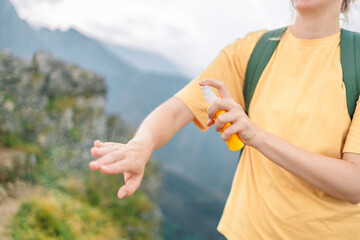 Young woman travel spraying insect repellents on skin with spray bottle during hike in nature top...