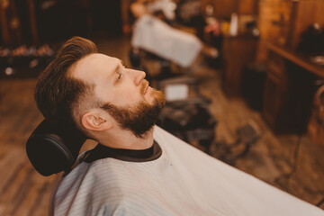 Obraz premium Barbershop concept, vintage color. Portrait happy client man in chair, top view