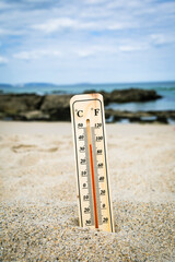 Thermometer on the beach marking high temperatures. Climate change. Global warming. Ecological...
