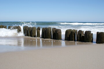 Beautiful coast of the Baltic Sea in Poland. Endless sandy beach, sea water waves. Wooden palisade...
